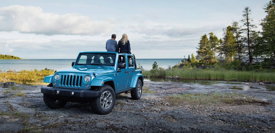 A blue 2018 Jeep Wrangler parked near a lake