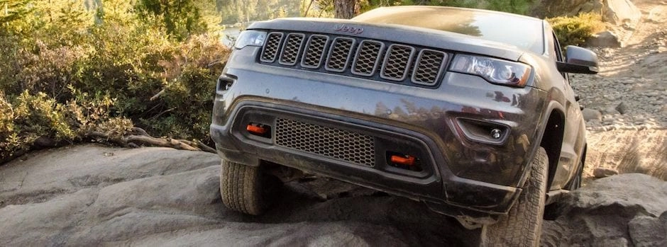 A Jeep Grand Cherokee driving up a steep, rocky hill