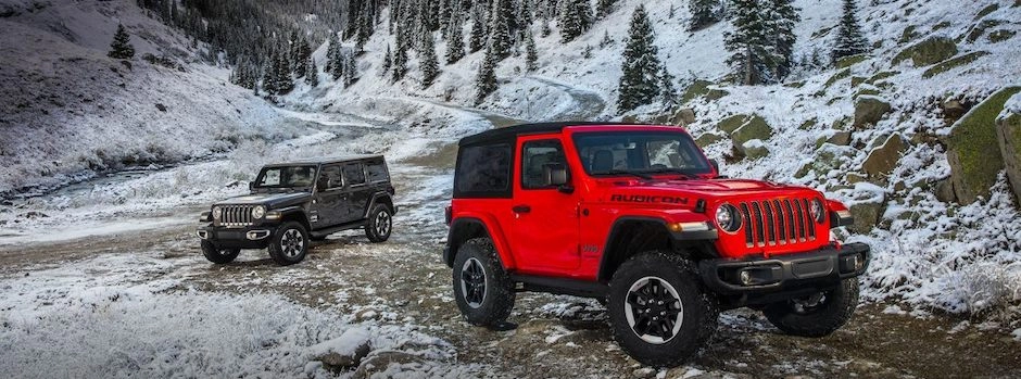 Two Jeep Wranglers parked by the mountains